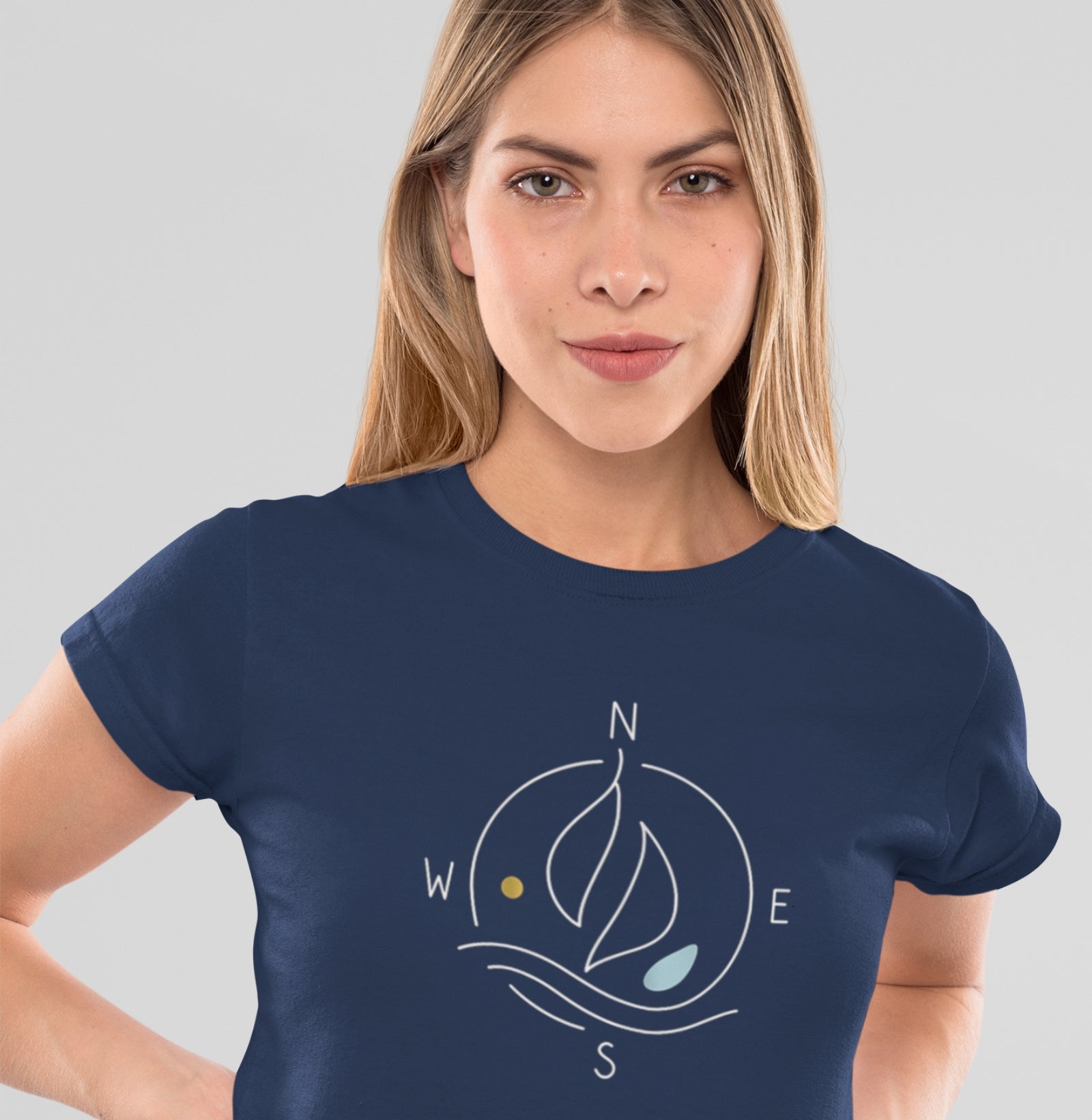 Mulher vestindo camiseta azul marinho Between Four Winds da Latitude23, com estampa minimalista de bússola e velas que remetem à essência náutica da marca.