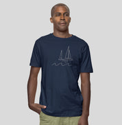 Homem vestindo camiseta azul marinho Between Waves da Latitude23, com estampa minimalista de veleiro e ondas, refletindo elegância e calma náutica.
