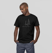 Homem usando camiseta preta Between Waves da Latitude23, com estampa minimalista de veleiro sobre ondas, simbolizando equilíbrio e estilo náutico moderno.