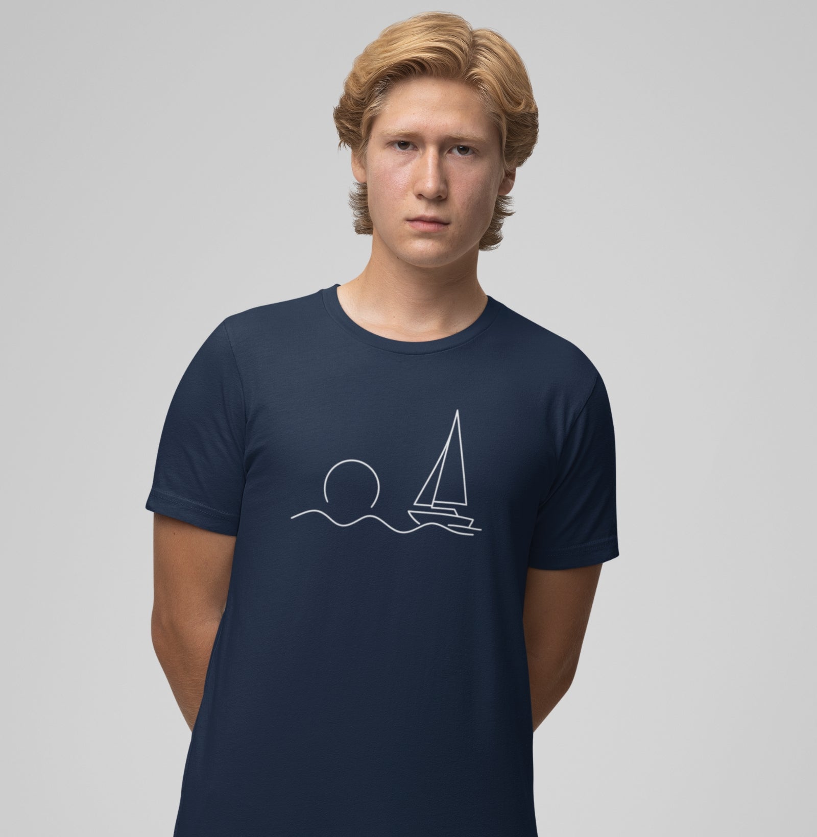 Homem usando camiseta azul marinho Beyond the Sail da Latitude23, com estampa minimalista de veleiro e sol, representando calma e horizonte náutico.