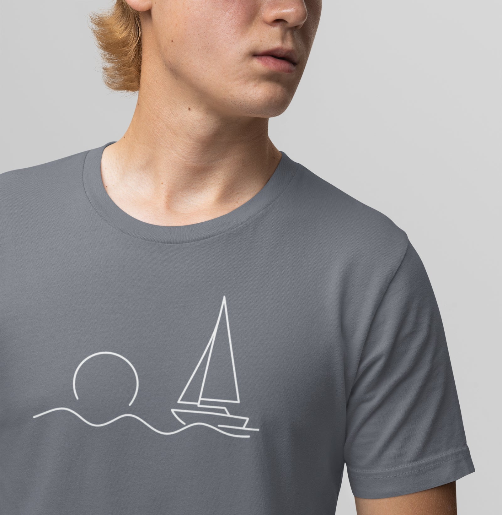 Detalhe da camiseta cinza Beyond the Sail da Latitude23, com estampa minimalista de veleiro e sol, simbolizando serenidade e espírito do mar.