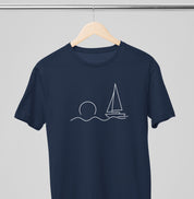 Camiseta azul marinho Beyond the Sail da Latitude23 pendurada em cabide, com estampa minimalista de veleiro e sol representando calma e elegância náutica.