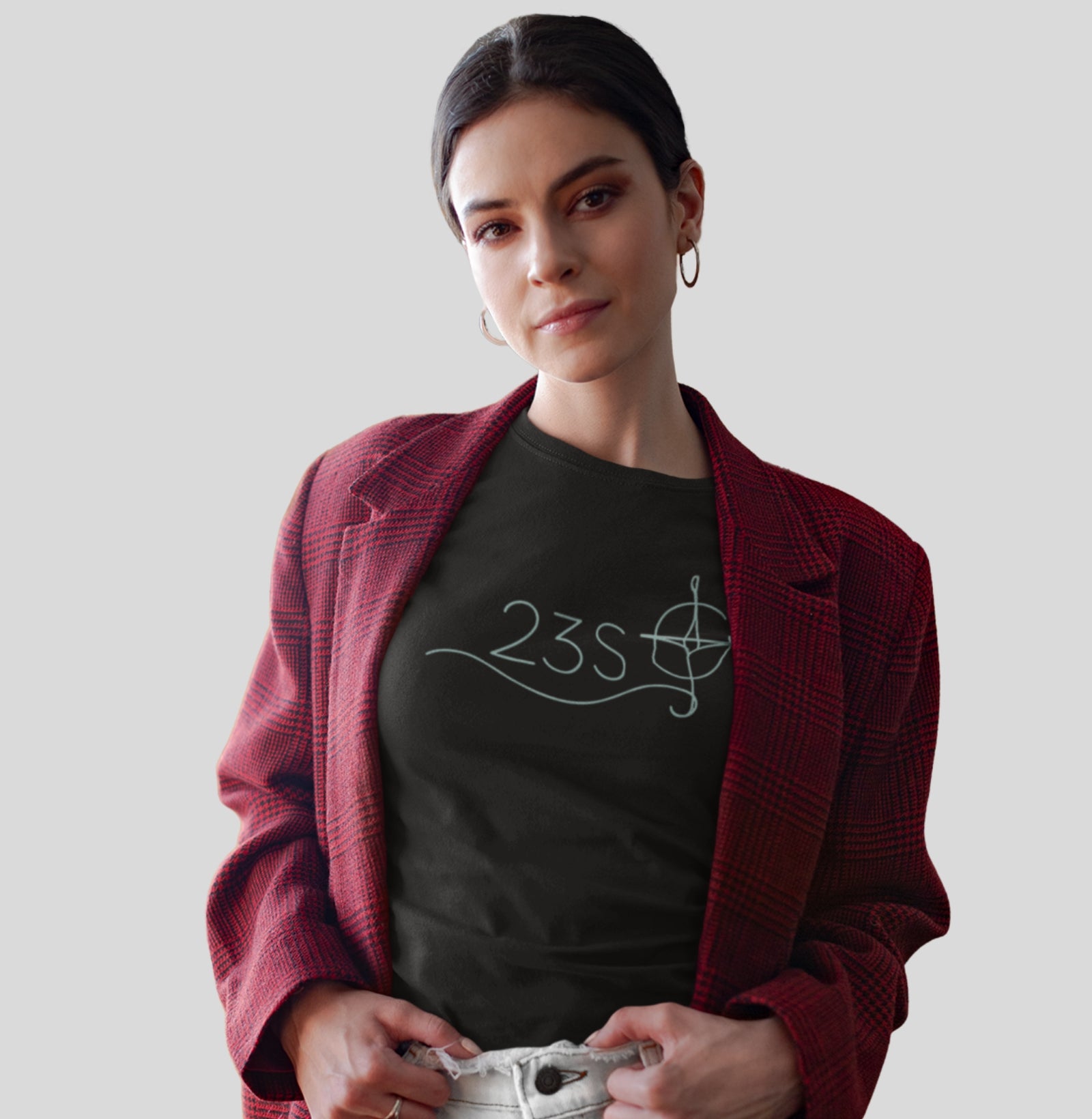 Camiseta preta Blue Axis da Latitude23 com design minimalista 23S e bússola em traço contínuo, usada por mulher com blazer xadrez vermelho em pose confiante.