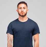Camiseta azul marinho Coastal Line da Latitude23 com design minimalista do traçado da costa e coordenada 23S, usada por homem com tatuagem no braço esquerdo.