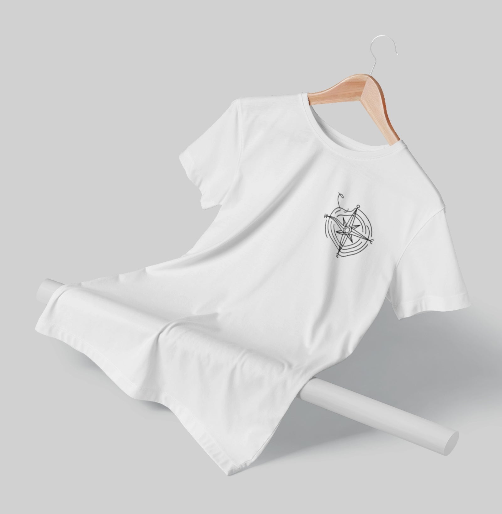 Camiseta branca Guiding Wind da Latitude23 dobrada sobre fundo neutro, exibindo a estampa de rosa dos ventos e o design minimalista com inspiração náutica.