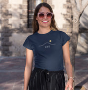 Camiseta azul marinho Horizon 23°S da Latitude23 com design minimalista do horizonte e sol dourado, usada por mulher sorridente com óculos de sol em ambiente urbano.