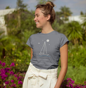 Mulher sorrindo ao ar livre usando camiseta cinza Horizonte de Prata da Latitude23, com estampa de veleiro sob a lua, simbolizando leveza e espírito náutico.