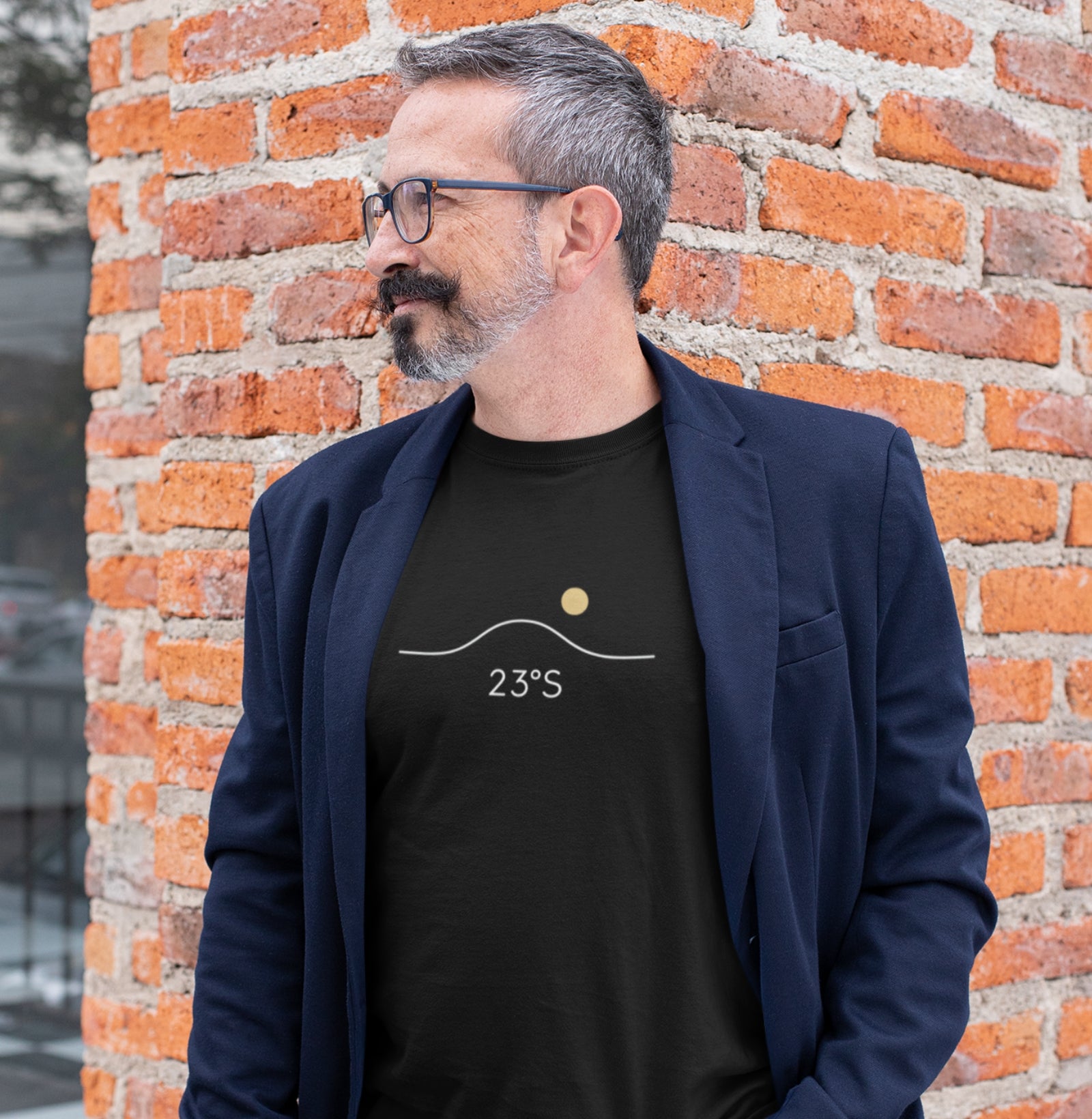 Homem usando camiseta preta Line Twenty-Three da Latitude23 com blazer azul, em ambiente urbano, exibindo estampa 23°S minimalista que simboliza o equilíbrio do sul.
