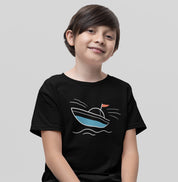 Menino vestindo camiseta preta Open Horizon da Latitude23, com estampa minimalista de barco azul e bandeira vermelha, inspirada na leveza do mar.