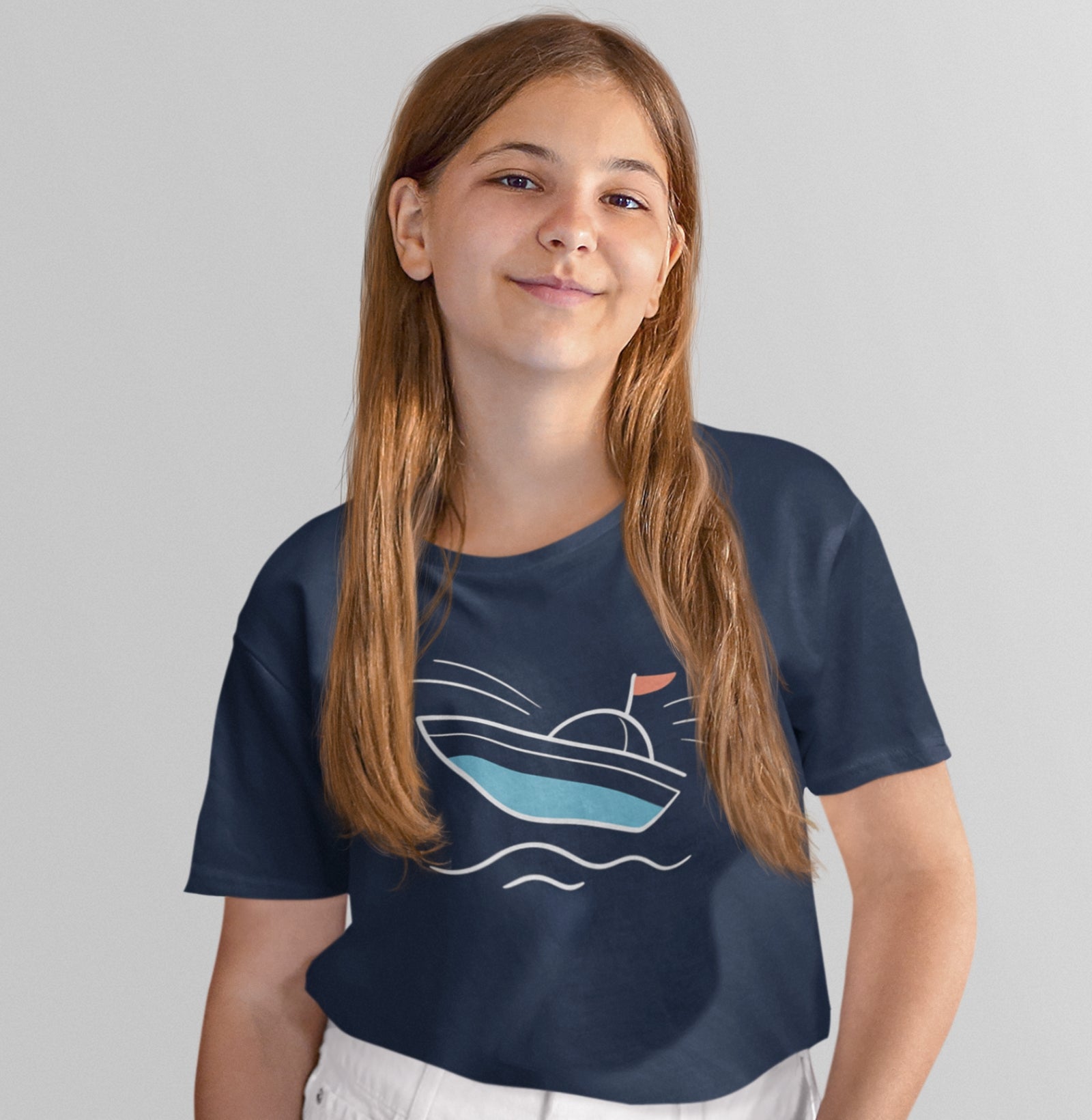 Menina usando camiseta azul marinho Open Horizon da Latitude23, com estampa de barco minimalista em azul e vermelho, transmitindo leveza e espírito marítimo.