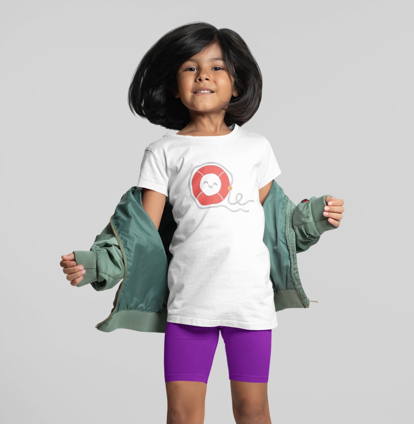 Menina usando camiseta branca Sea Hugger da Latitude23 com estampa de boia vermelha sorridente, transmitindo leveza, proteção e o encanto do mar.