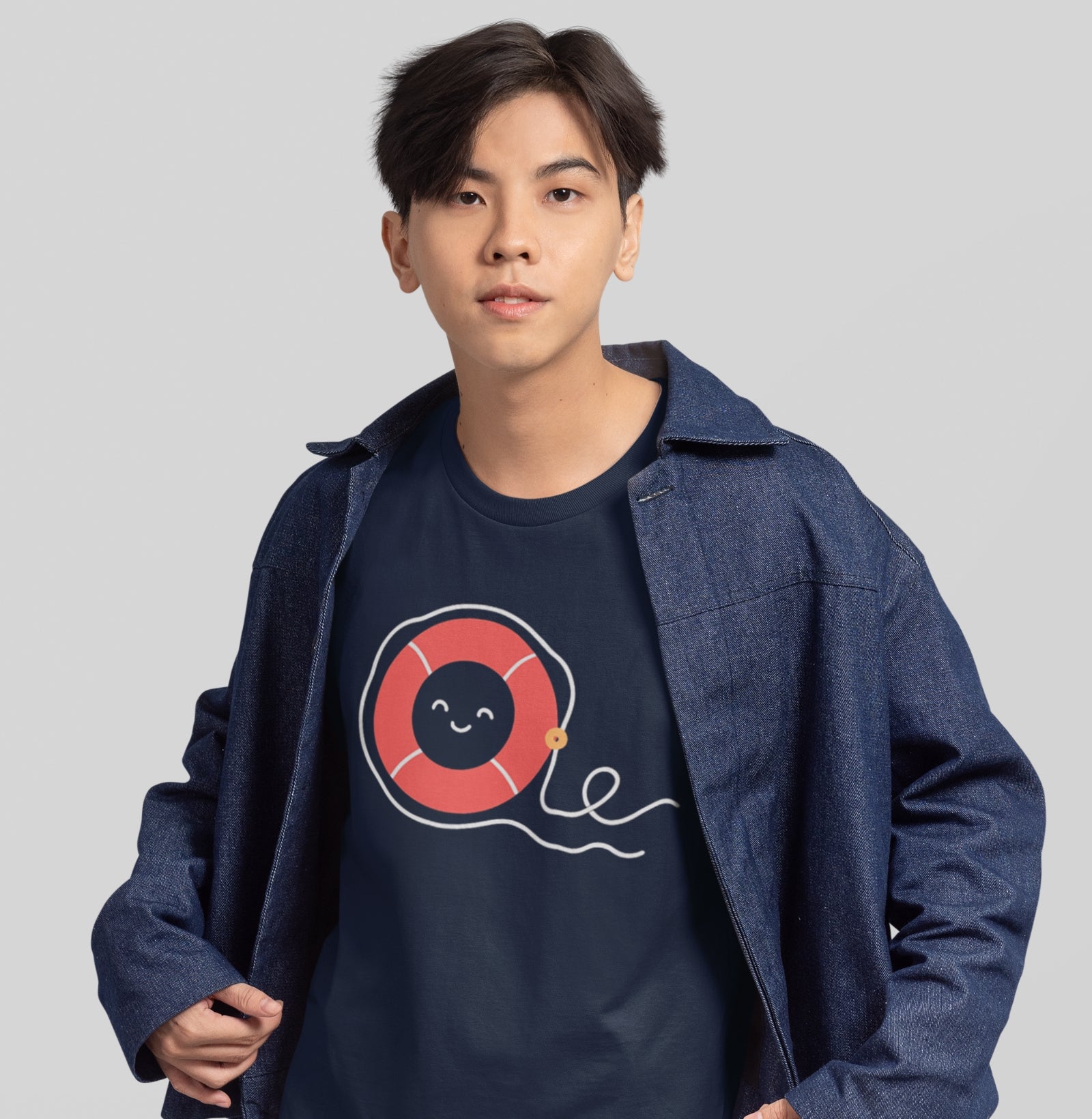 Adolescente usando camiseta azul marinho Sea Hugger da Latitude23, com estampa minimalista de boia vermelha sorridente que reflete o espírito leve e náutico da marca.